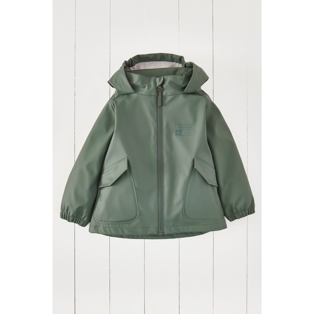 A sage green hooded rain jacket with a front zipper, elastic cuffs, and large front patch pockets, displayed against a white vertical wood plank background.