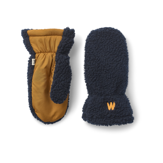 A pair of winter fleece pile mittens by Liewood with a contrast waterproof panel, shown on a clean white background. One mitten is oriented to show the interior with a mustard yellow lining and dark navy blue sherpa trim, while the other shows the exterior with a matching navy blue sherpa cuff featuring a small orange embroidered 'W' logo.